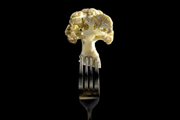 Cauliflower on a fork in black background . close up . vegetable Vegetarian and vegan concept.