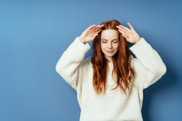 Pretty young woman holding back her long red hair