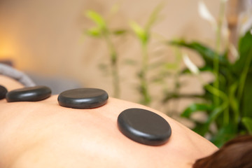 Health spa relaxing stone therapy with hot volcanic stones on back