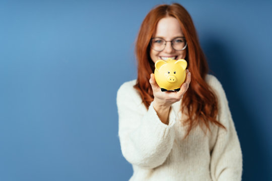 Smiling Successful Woman Holding Up A Piggy Bank