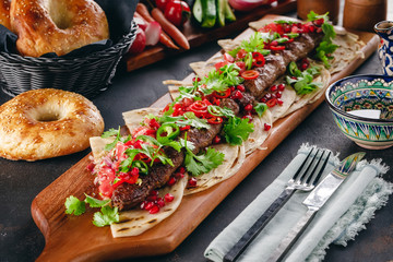 Lula Kebab on the wooden service plank with garnet and arabic bread