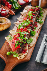 Lula Kebab on the wooden service plank with garnet and arabic bread