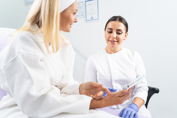 Dermatologist looking at a cosmetic product in her patients hand