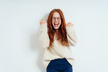 Exultant young redhead woman cheering