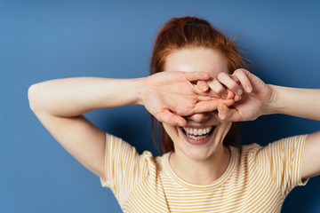 Laughing young woman covering her eyes