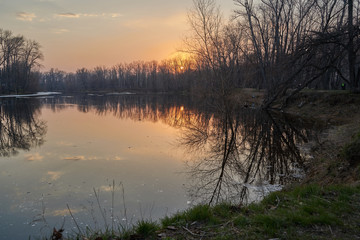    Early spring. Morning dawn over the lake in a misty, thoughtful haze. Beautiful view of the forest covered with fog early in the morning. The sun's rays of light.       