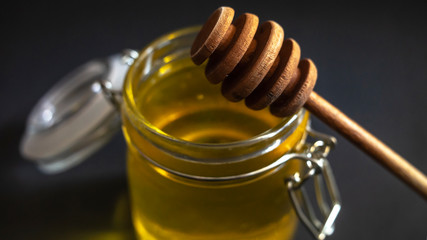 fresh Golden bee honey, with a wooden stick lying on a glass jar, close-up