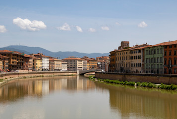 Fototapeta na wymiar A view of Arno river in Florence, Italy, with pastel townhouses on both sides reflecting in the water.