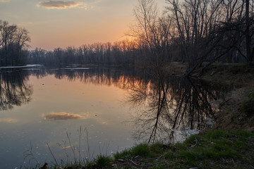    Early spring. Morning dawn over the lake in a misty, thoughtful haze. Beautiful view of the forest covered with fog early in the morning. The sun's rays of light.       