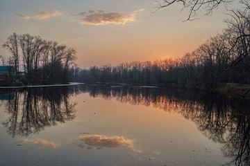    Early spring. Morning dawn over the lake in a misty, thoughtful haze. Beautiful view of the forest covered with fog early in the morning. The sun's rays of light.       