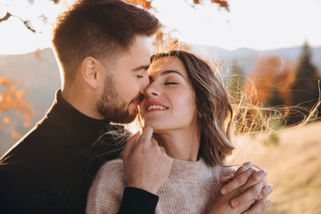 Stylish young couple in the autumn mountains. A guy and a girl hug together under a large old tree...