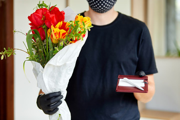 Courier, delivery man in medical latex gloves safely delivers online purchases a bouquet of flower
