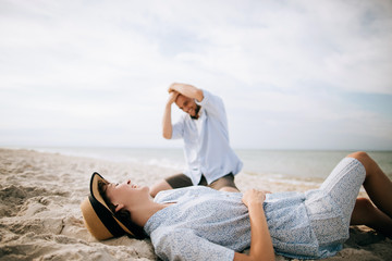 Man and woman lie on a deserted sea beach and hug. Summer vacation