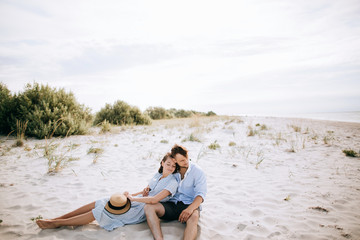 Couple sitting on the beach on the sand and dreaming.