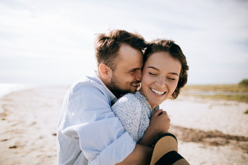 Happy young couple hugging on the sea beach and smiling. Honeymoon at sea