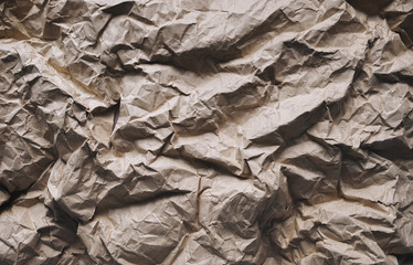 Brown background from heavily crumpled vintage paper, which is used as a wrapper. The texture of cardboard made from recycled materials.