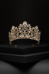 Subject shot of a golden tiara adorned with a lot of diamond-like gems and clear sparkling...