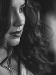 Beautiful young woman with perfect dark curly hair and beautiful make-up with puffy red lips. Close-up. Black and white art photo. Soft selective focus.