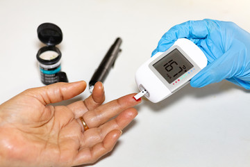 Medical examiner taking blood sample from a female patient for instant blood sugar measurement shot...