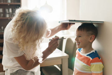 Mother playfully measuring the height of her son