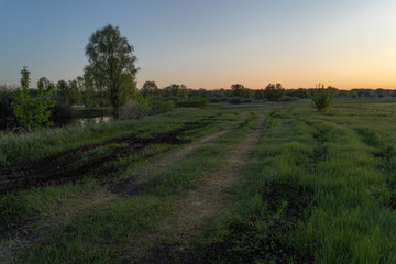 Fototapeta premium Dawn over the lake. Beautiful evening blue sky at sunset with flaming bright light clouds. Warm summer evening at sunset. May.