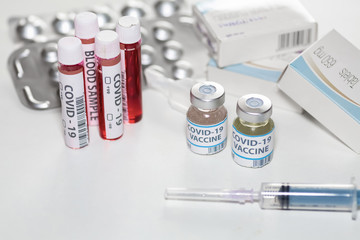 Vaccine bottles with injection syringe, blood sample vials and medical drugs at a healthcare center for detection and treatment of Coronavirus patients