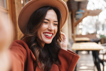 Image of joyful elegant adult woman laughing and taking selfie photo