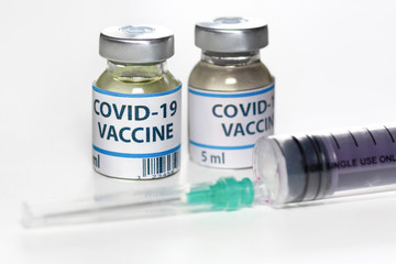 Coronavirus vaccine bottles with injection syringe on white background shot with selective focus