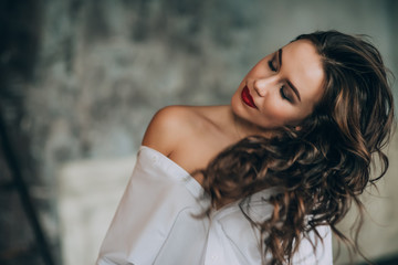 Fashionable young woman with perfect dark curly hair and beautiful make-up with puffy lips in an...