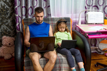 Dad and daughter are sitting with laptops on the couch.