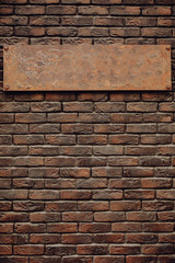 Old blank metal sign on a brown brick wall. The sign looks expensive.