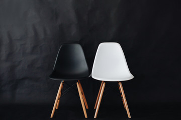 Stylish concept with white and black chairs on a black background.