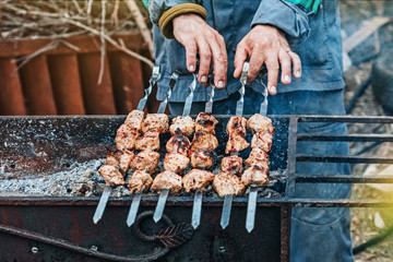 a man fries kebabs on the grill in his infield.