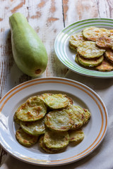 fresh raw zucchini and fried zucchini in plates on a wooden table close-up