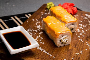 Rolls with curd and cream cheese. Wooden tray. Cup with soy sauce