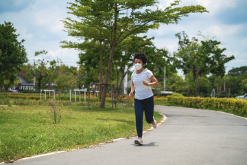 Asian woman wearing face mask while she running in public park after coronavirus outbreak and city lockdown a new normal life. social distancing, new normal, covid-19 or running concepts