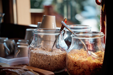 A breakfast buffet with cereals and oats in bowls at a mountain cabin during sunrise.