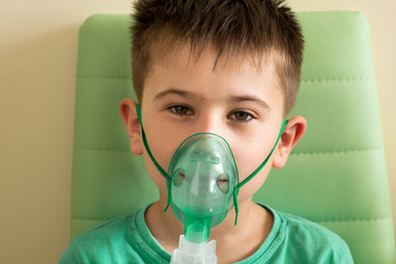 Little boy making inhalation with nebulizer at home. Asthma attack concept