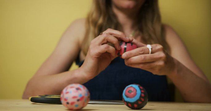 Woman decorating easter eggs against a yellow background