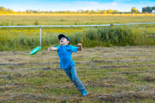 Boy jumping with frisbee outdoors on sunset. Summer holidays concept