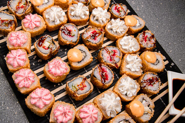 Seth rolls on a black background. Photo for the menu. A cup with sauce. Chinese chopsticks