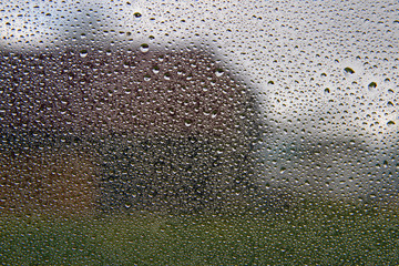 Water drops on window and rural landscape.
