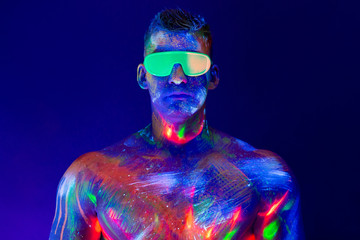 .Portrait of a pumped-up man at a disco. Fluorescent paint on face in with UV light