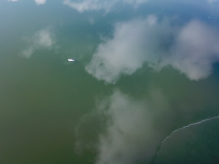 Fototapeta premium Aerial drone shot flying over fishermen in a small fishing boat on a sea. Beautiful winter landscape ocean. Aerial View. Drone shot over a beautiful lake