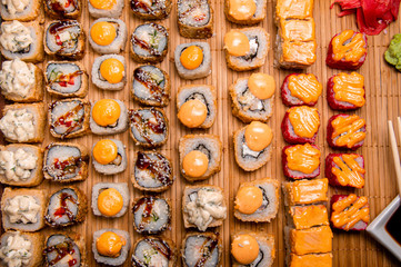 Set of baked rolls on a brown tray. Photo for the menu. A cup with sauce. Chinese chopsticks