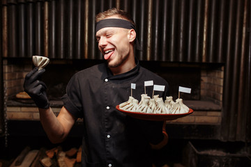 Cheerful chef posing with a serving of Khinkali. Georgian national traditional cuisine. Cooking process. Kitchen. Food concept