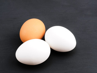 Three white and brown eggs on a black wooden background. Healthy eating concept