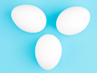 Three white chicken egg on a blue background. Healthy eating concept