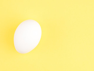 One white chicken egg on a yellow background. Healthy eating concept
