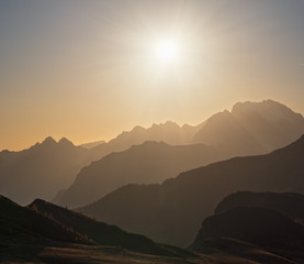 Sun glow in evening hazy sky and mountain silhouettes view.  Peaceful view from Giau Pass. Climate, environment and travel concept scene.